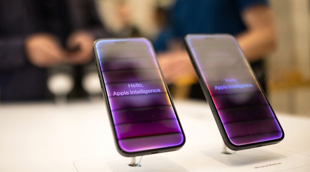 Two iPhones on a store display showing Hello, Apple Intelligence